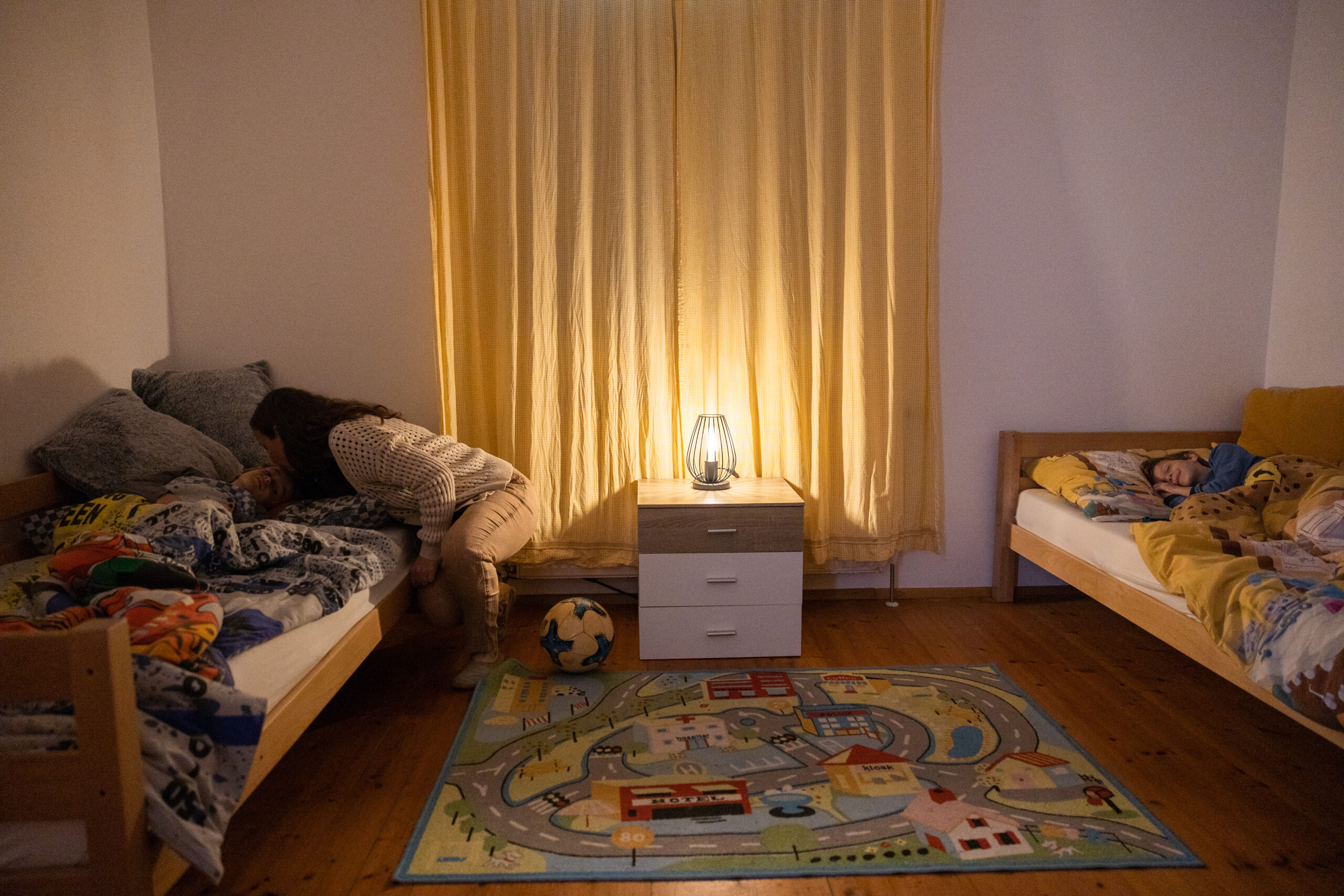 Mutter legt Kinder ins Bett.